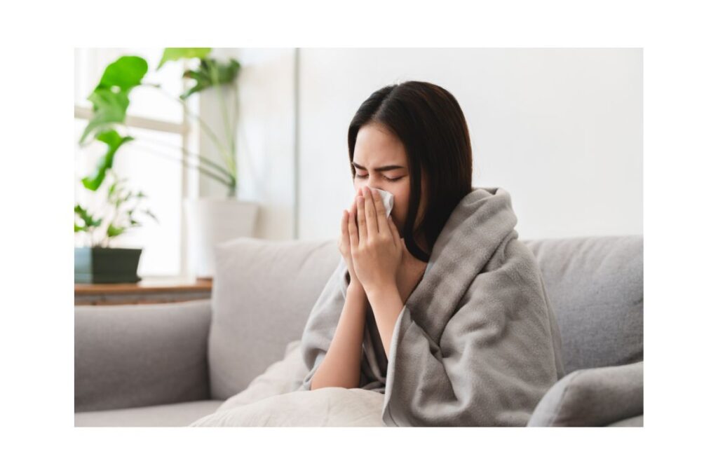 Girl wrapped in a blanket blows her nose.