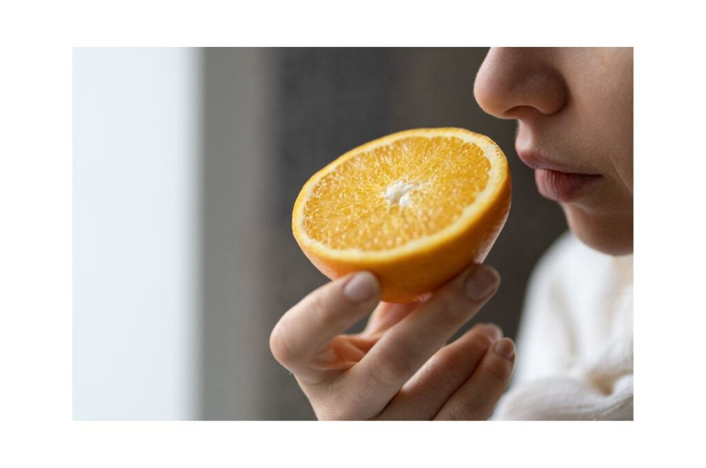 Woman hold half an orange up to take a bite.