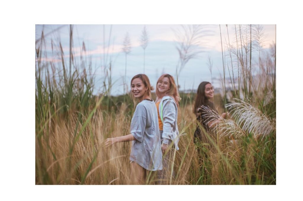 Three women walking in a field smiling together.