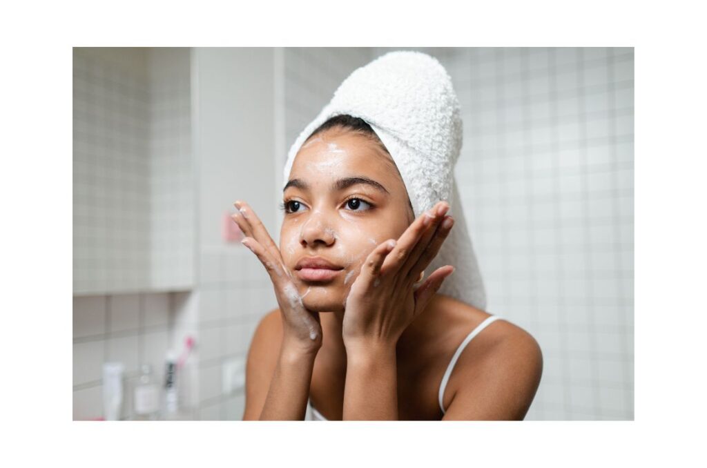 Girl with a towel around her dark hair, washig her face.